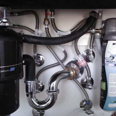 Under-sink plumbing with pipes, hoses, and water filter cartridges in a cabinet