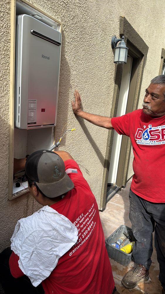 Two workers installing a wall-mounted electrical panel beside a house exterior