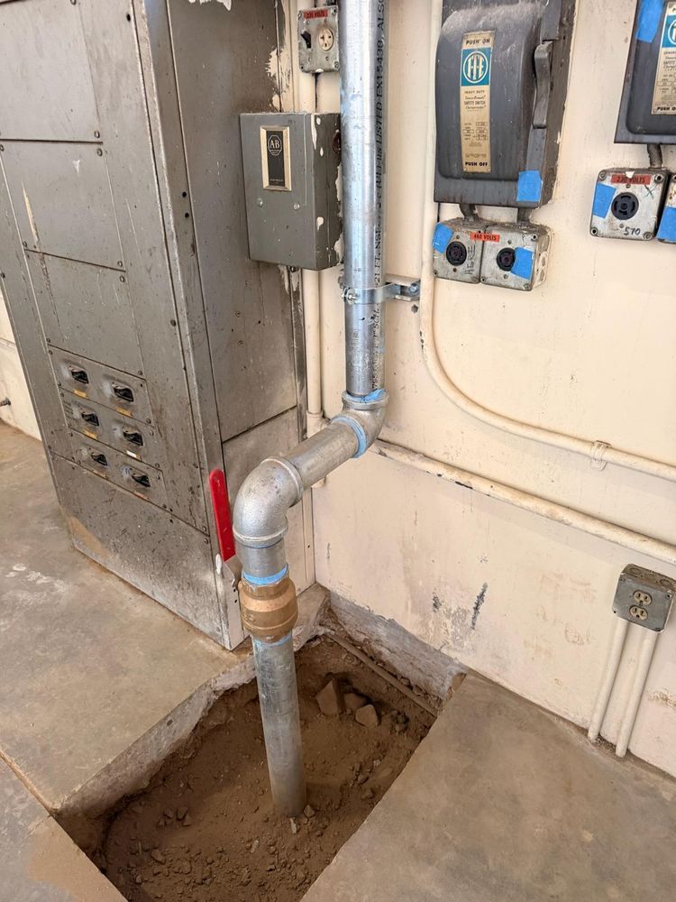 Red-handled gas shutoff valve on a pipe next to electrical panels and a wall-mounted meter.