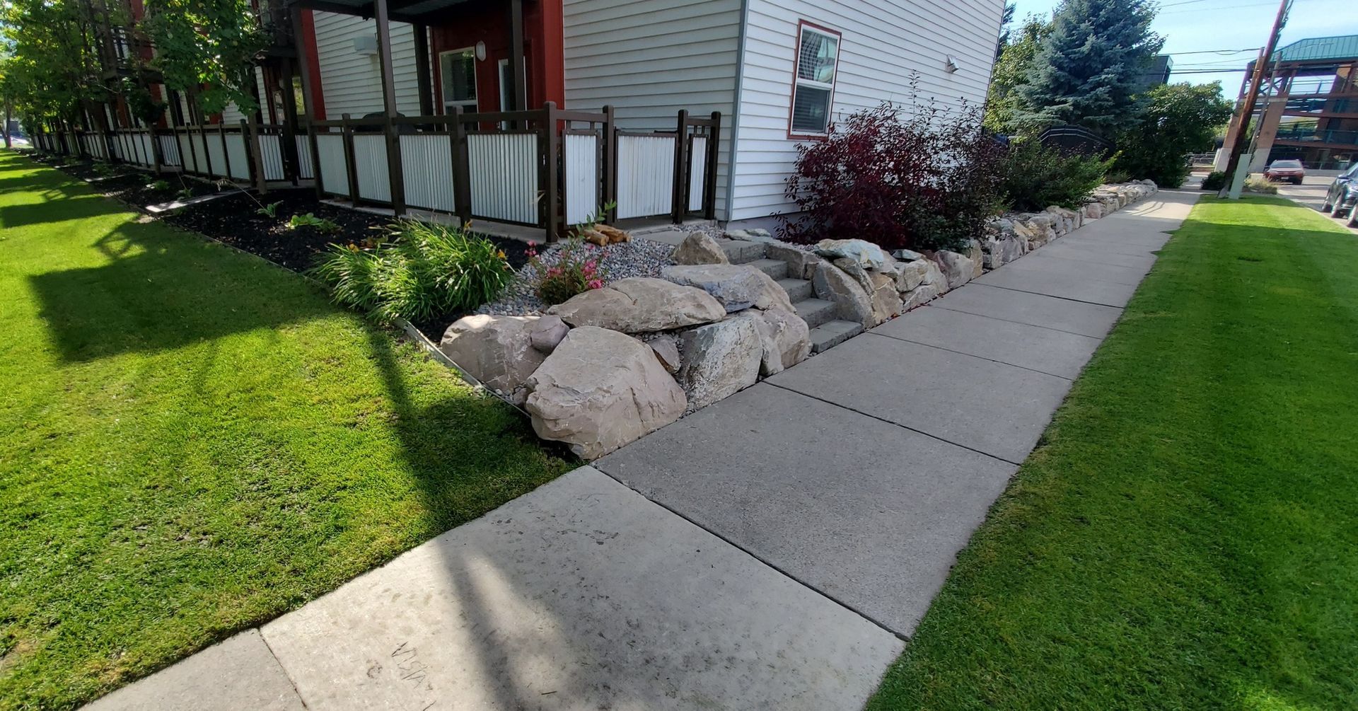 Stone wall bordering a sidewalk and lawn next to a building.
