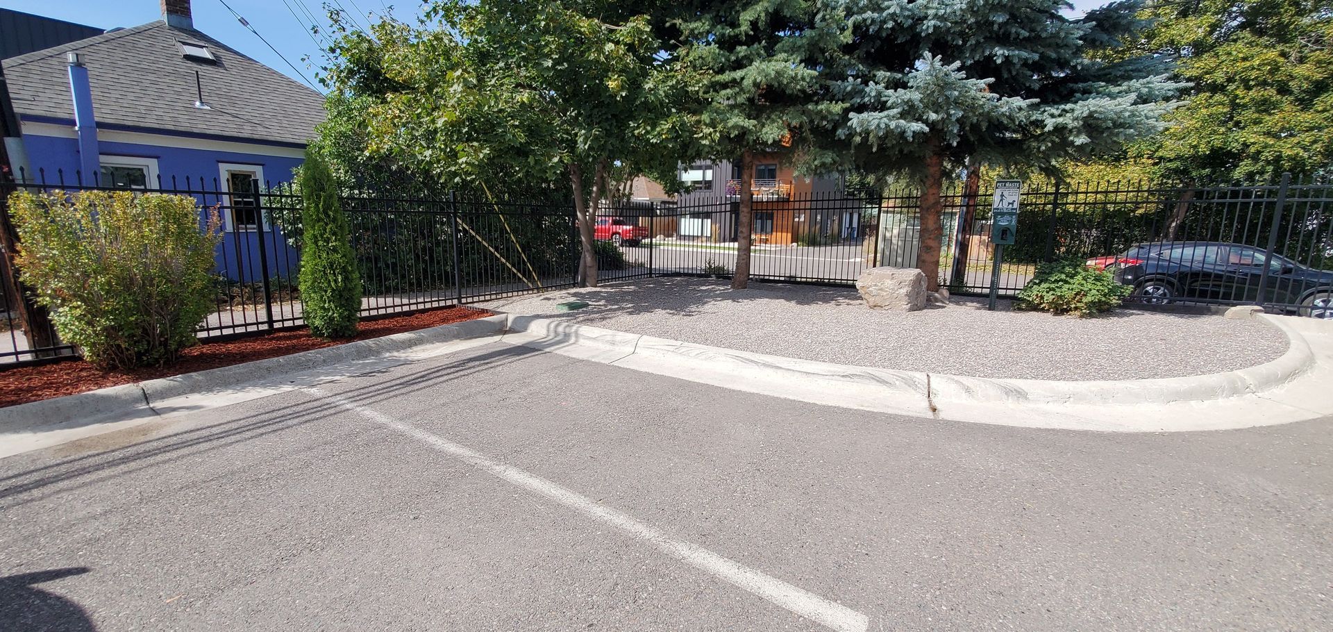 Parking lot with trees and a blue building in the background.