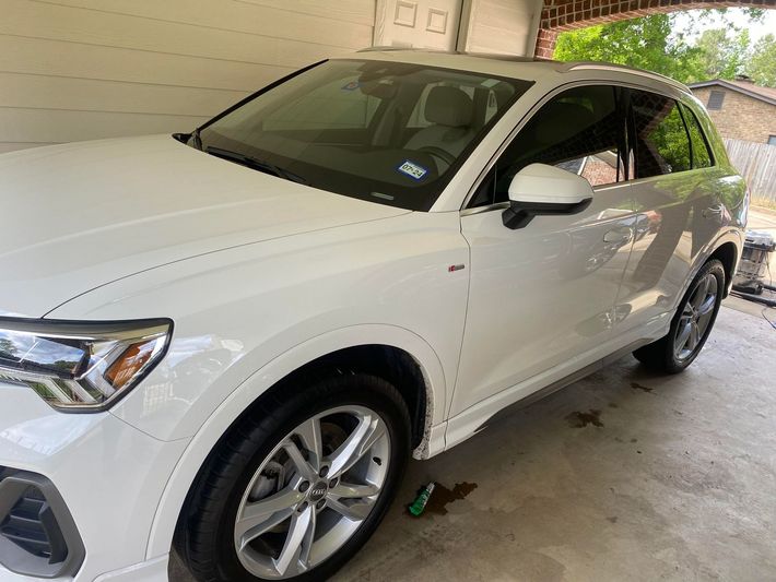 A white car is parked in a garage next to a garage door.