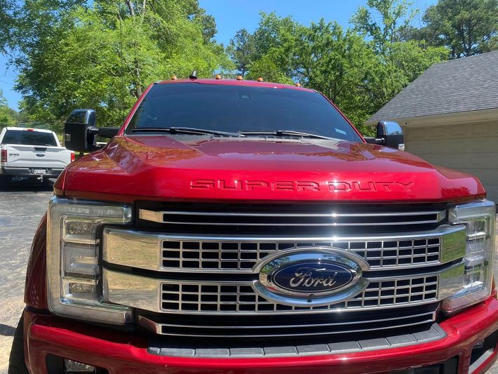 A red ford super duty truck is parked in front of a garage.
