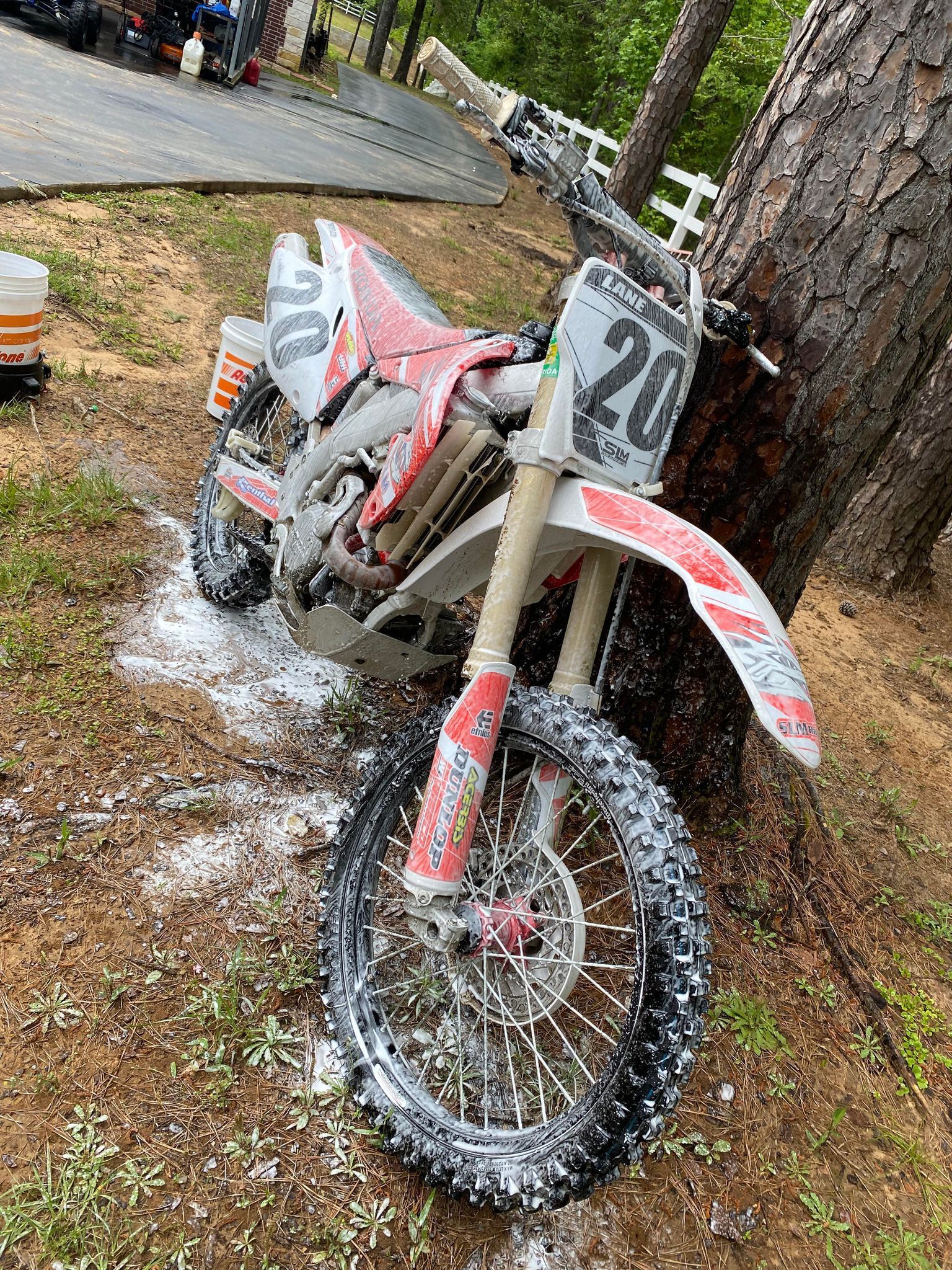 A dirt bike is sitting on the ground next to a tree.
