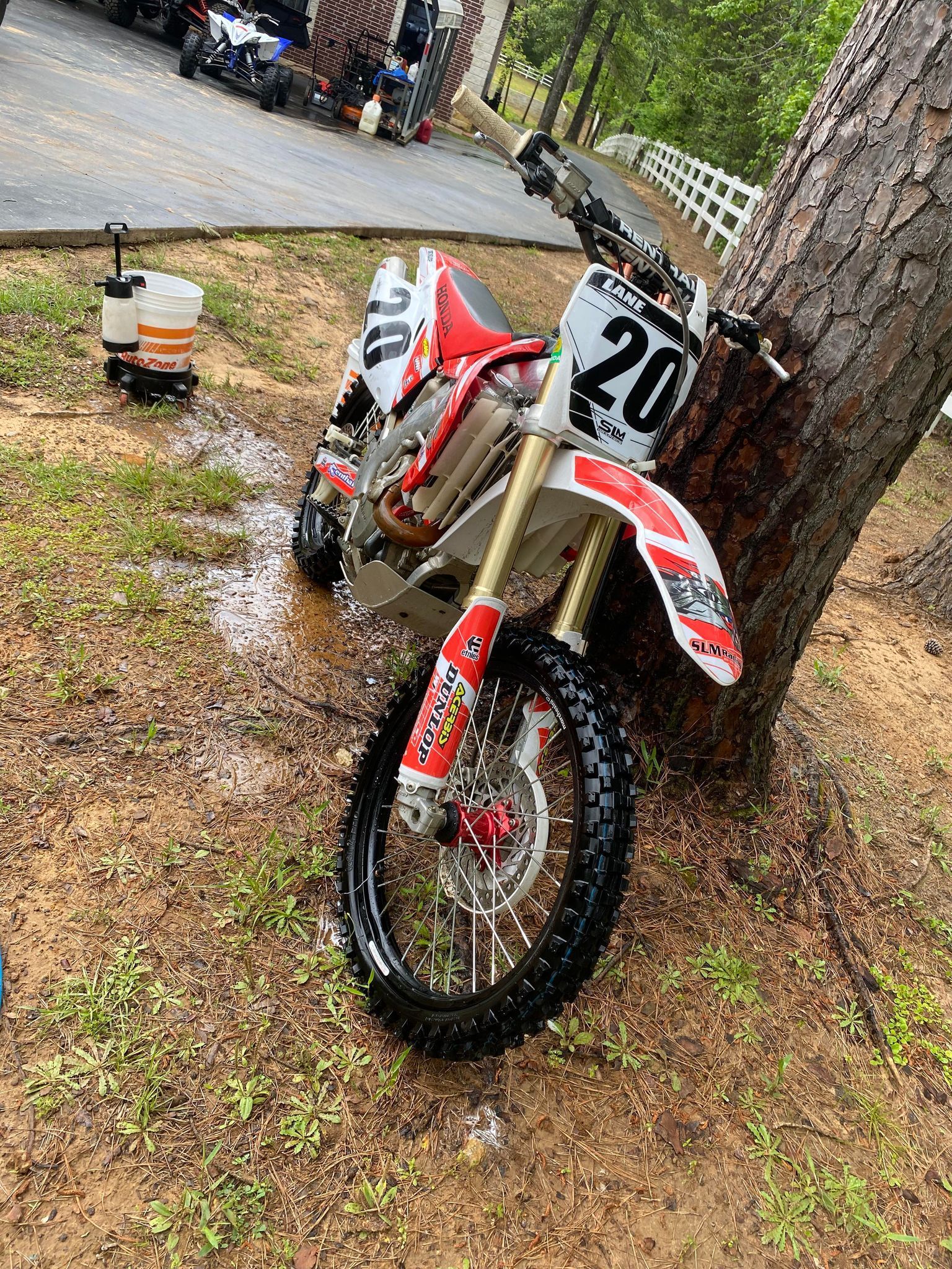 A dirt bike is parked next to a tree in the grass.