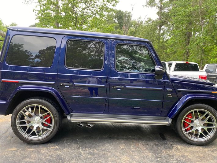 A blue mercedes benz g63 is parked in a parking lot.