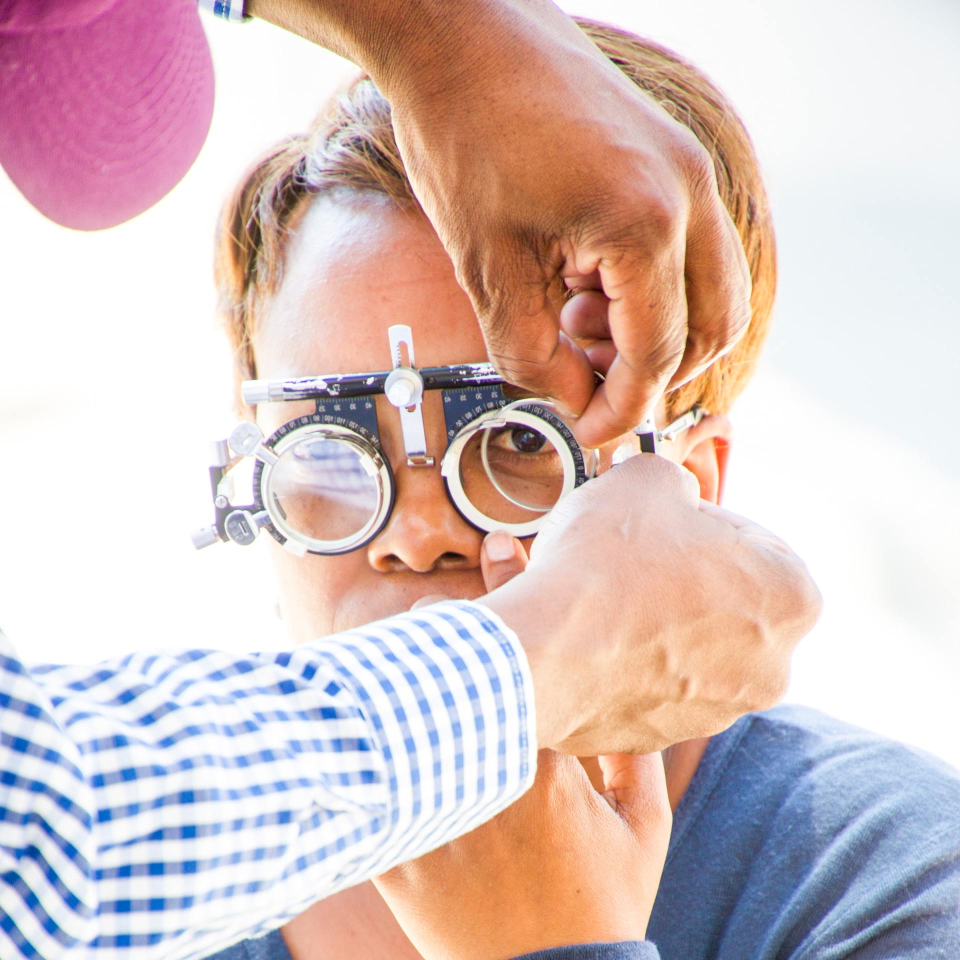 A man wearing a pair of glasses is being examined by another man