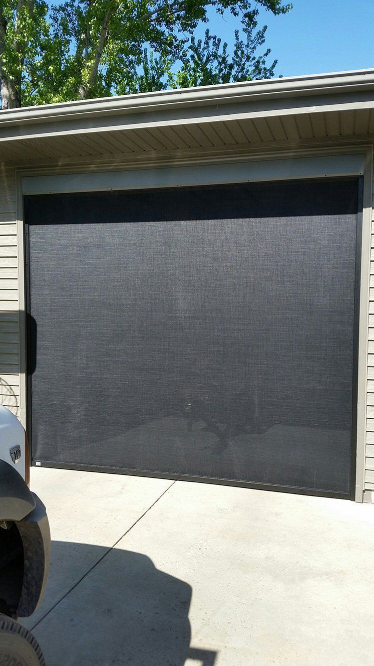 A garage door with a shade on it and a car parked in front of it.