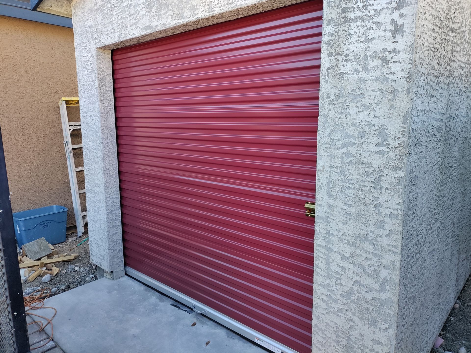 A red garage door is sitting on the side of a building.