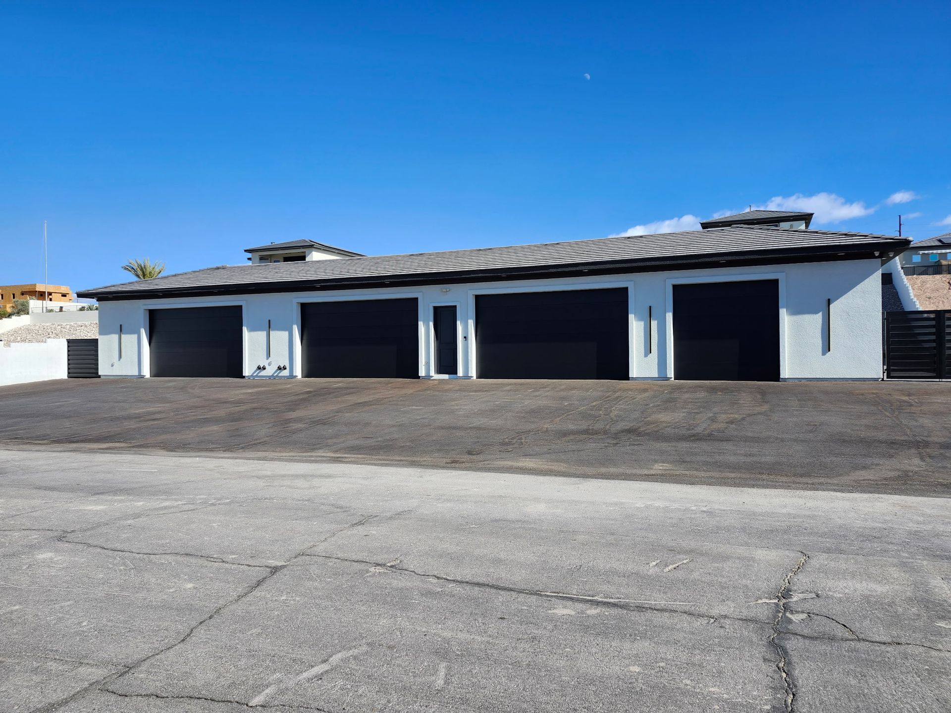 A white house with black garage doors on a sunny day