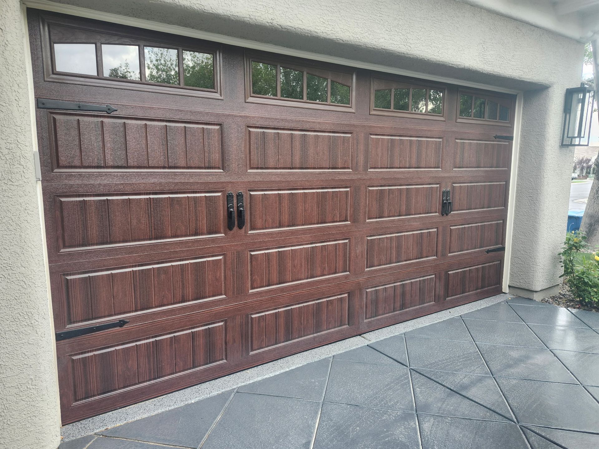 A large wooden garage door is on the side of a house.