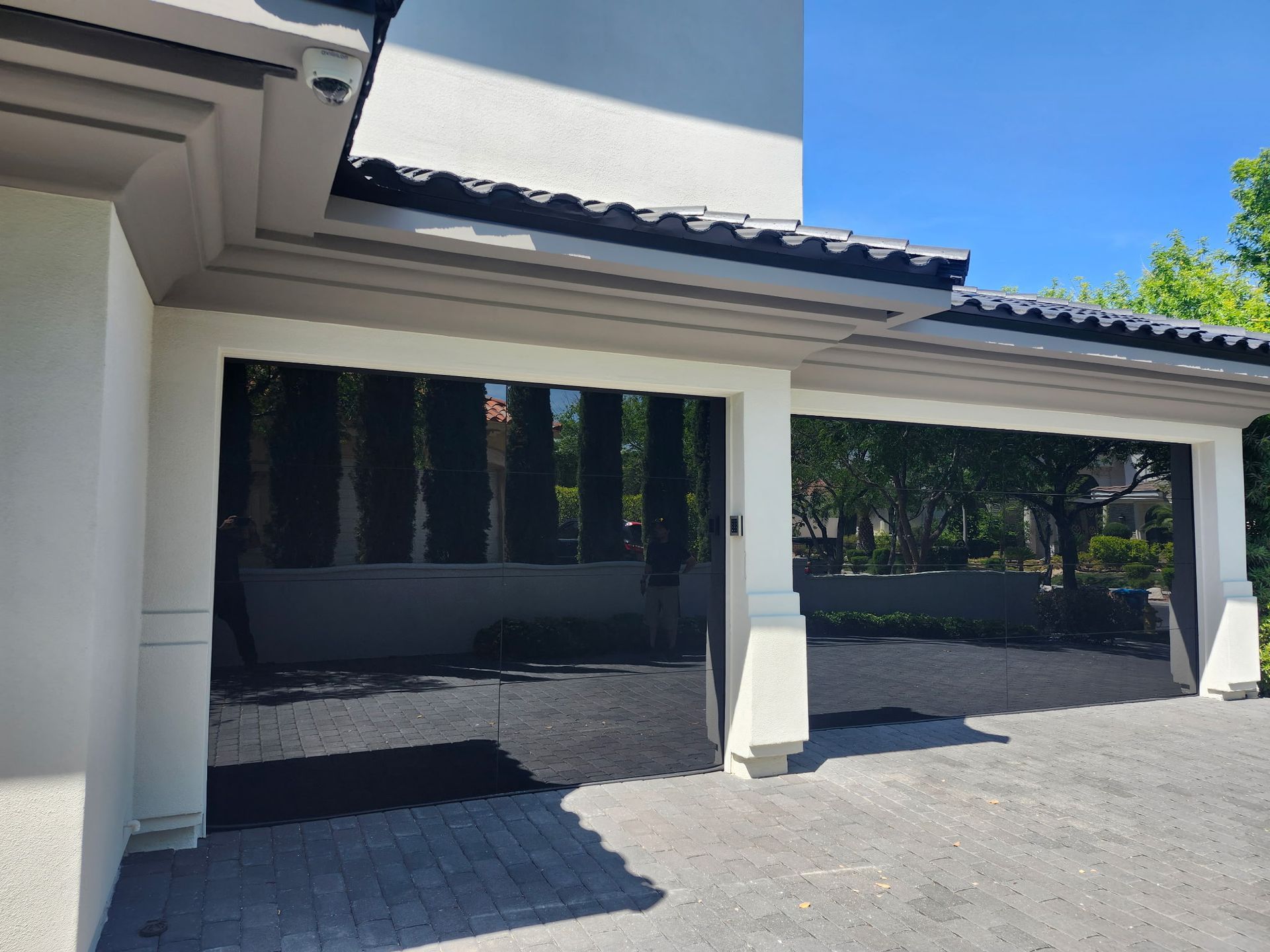 A white house with a black garage door and a driveway.