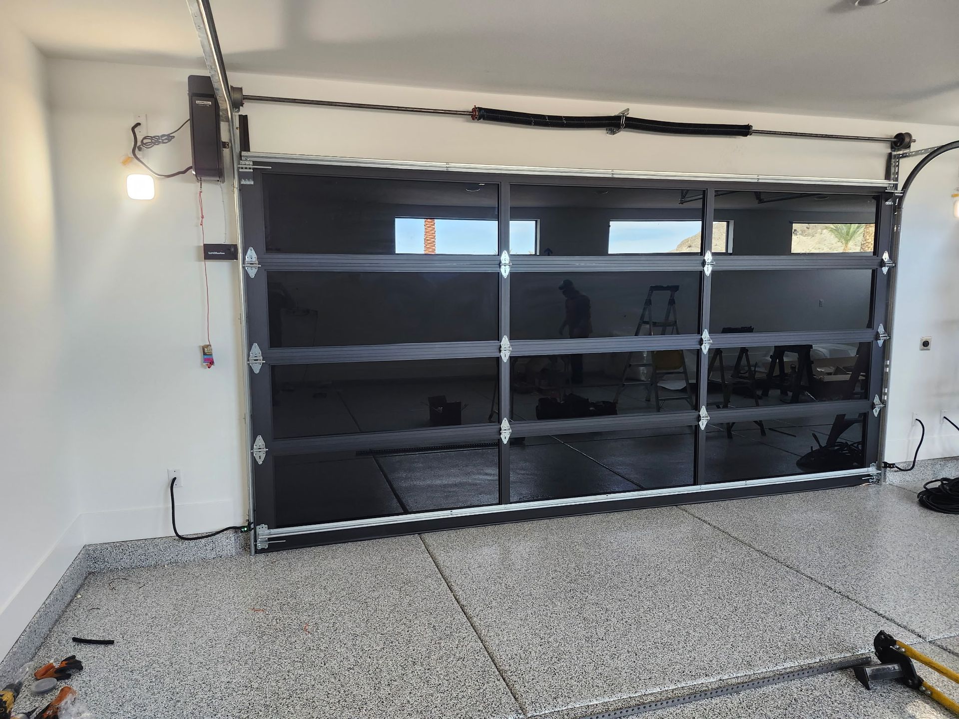 A black garage door is being installed in a garage.