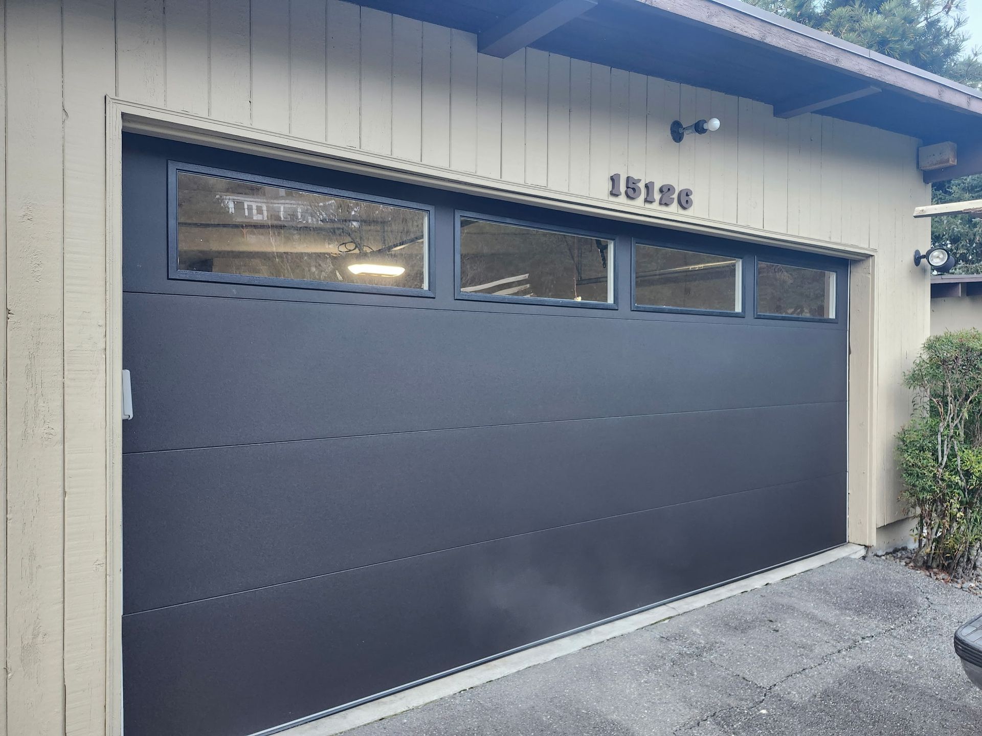 A black garage door is sitting in front of a house.