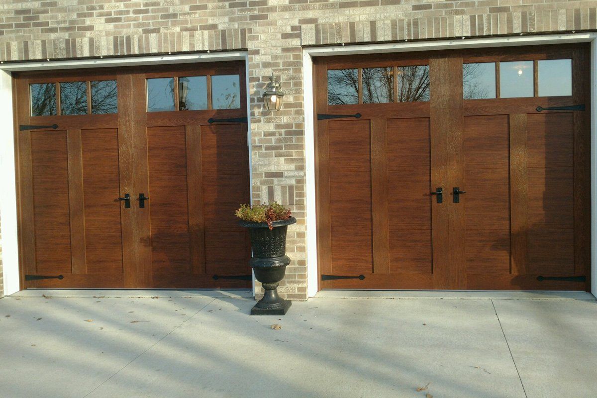 A pair of wooden garage doors next to a brick building