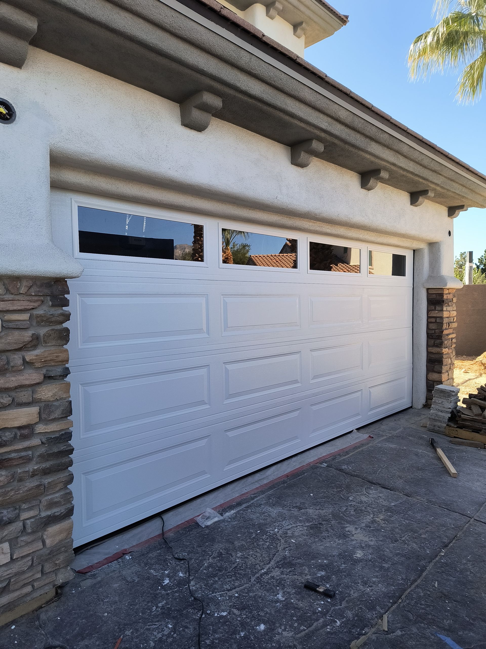 A white garage door with a stone wall behind it