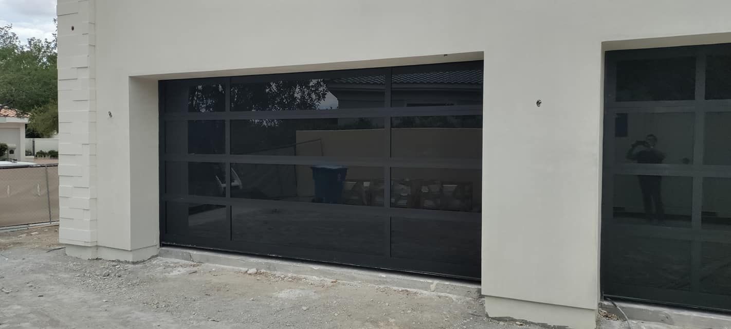 A black garage door is being installed on a white house.