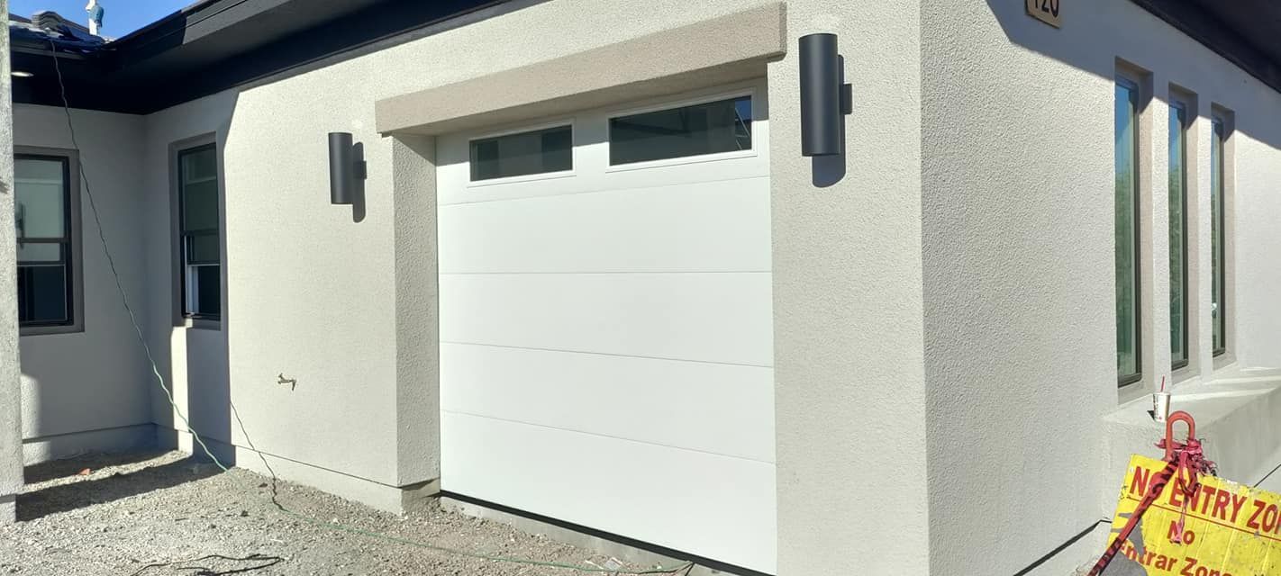 A white garage door is sitting in front of a white house.