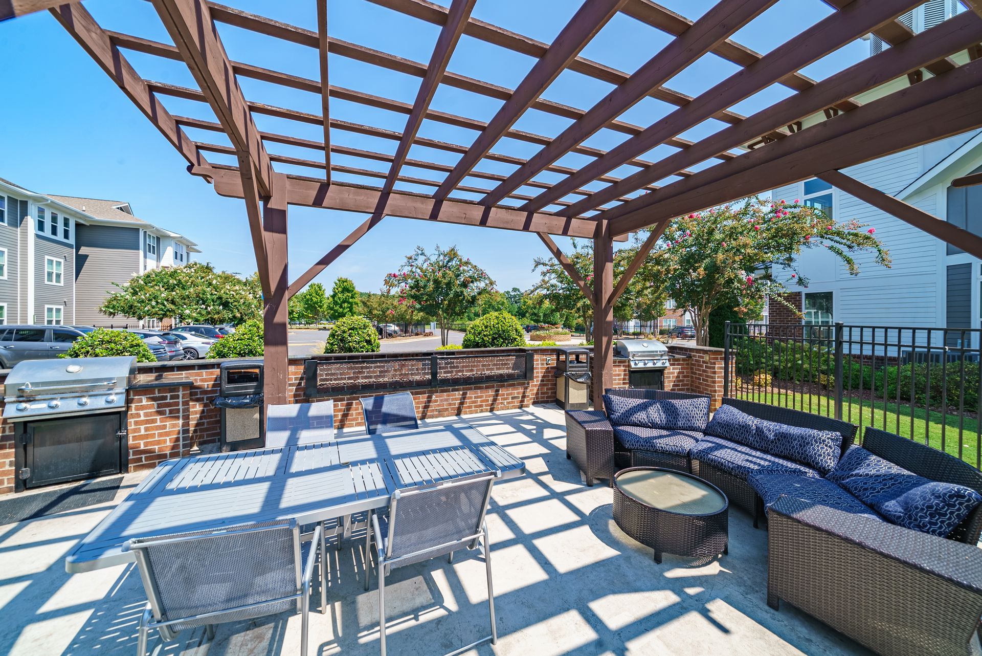 Outdoor patio with brown pergola, grills, seating, and a table at Willows at Fort Mill, offers pet-friendly apartments for rent near Downtown Fort Mill, SC.