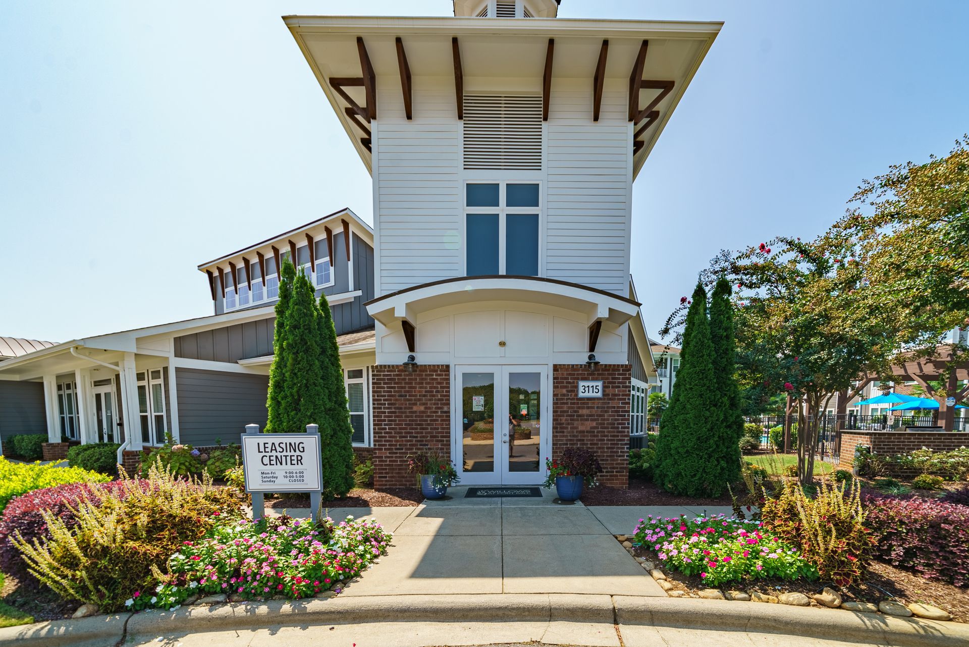 Entrance to an apartment complex office at Willows at Fort Mill, offers apartments for rent in Fort Mill, SC; white building, blue sky, landscaping.