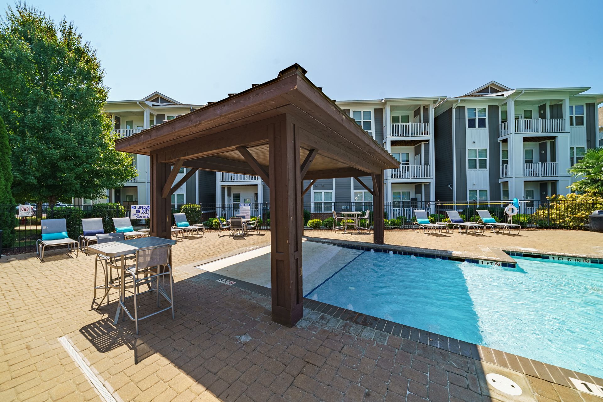 Poolside gazebo with pool, lounge chairs, and apartment building in the background at Willows at Fort Mill, offers apartments for rent near Downtown Fort Mill, SC.