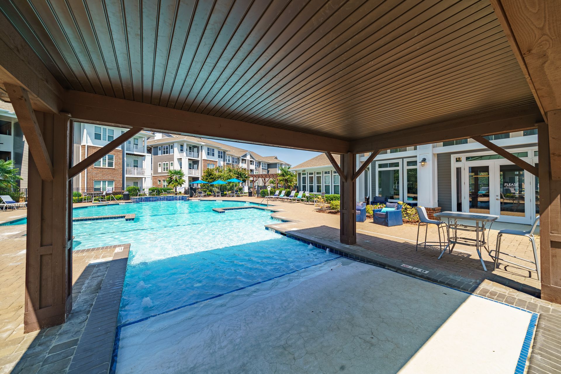 Poolside covered seating area with a pool in the background, sunny day at Willows at Fort Mill, offers apartments near Downtown Fort Mill, SC
