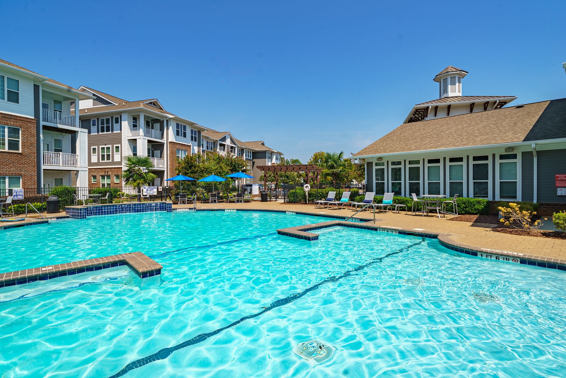 Swimming pool with buildings in the background on a sunny day at Willows at Fort Mill, offers pet-friendly apartments for rent in Fort Mill, SC.