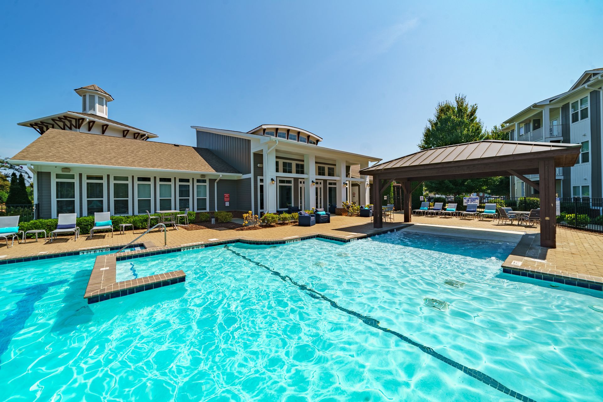 Swimming pool with a clubhouse and pergola on a sunny day at Willows at Fort Mill, offers pet-friendly apartments in Fort Mill, SC.