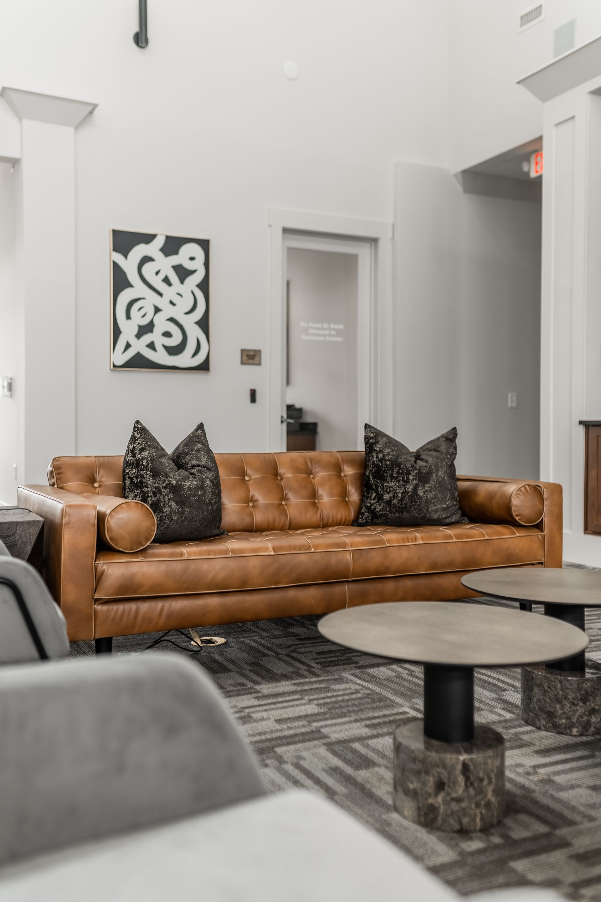 A tan leather sofa with patterned pillows in a modern resident lounge setting at Willows at Fort Mill, offers 1,2, and 3 bedroom apartments in Fort Mill, SC.