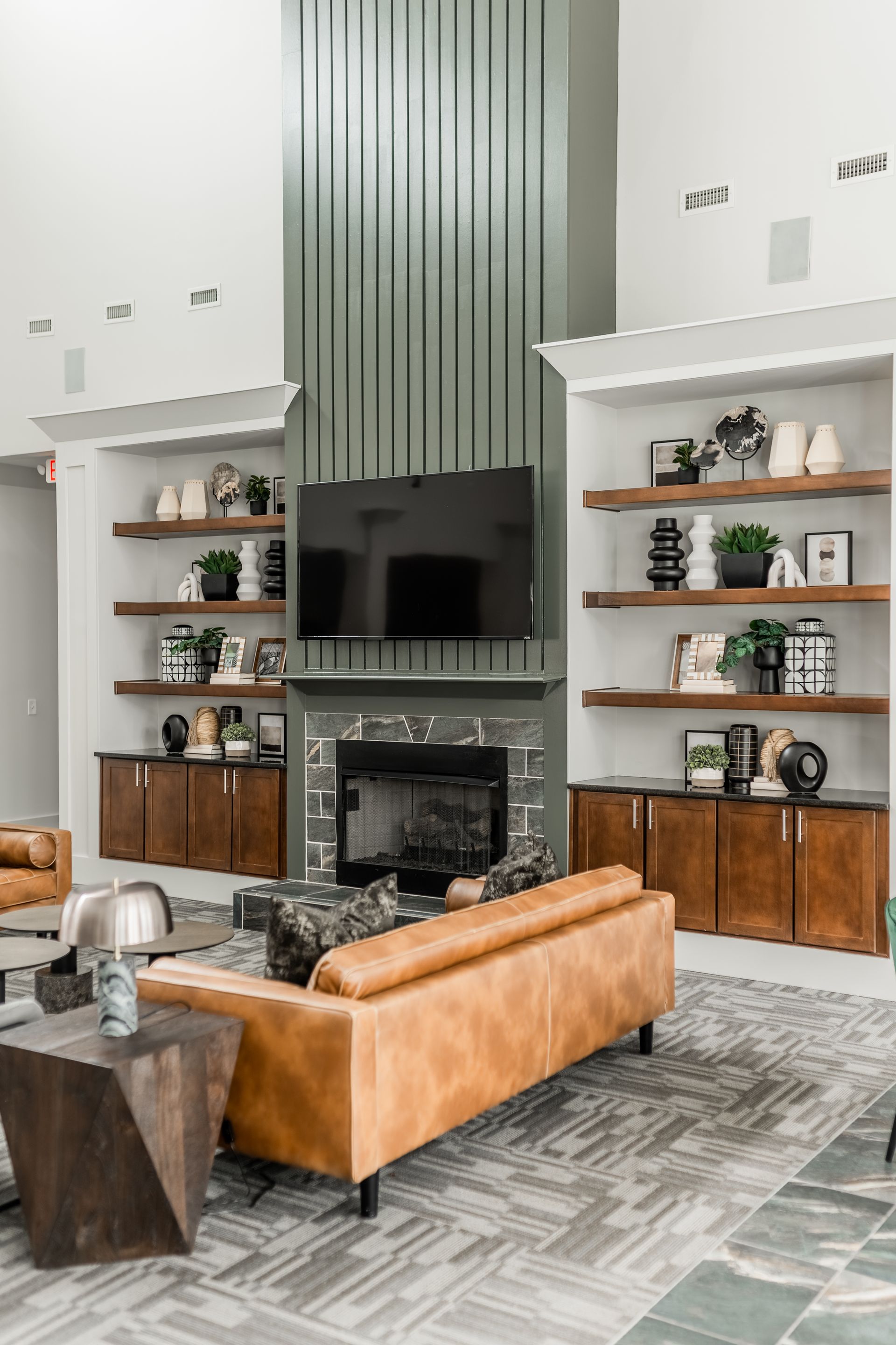 Resident clubhouse with a leather sofa, fireplace, built-in bookshelves, TV, and geometric side table at Willows at Fort Mill, offers 1,2, and 3 bedroom apartments in Fort Mill, SC.
