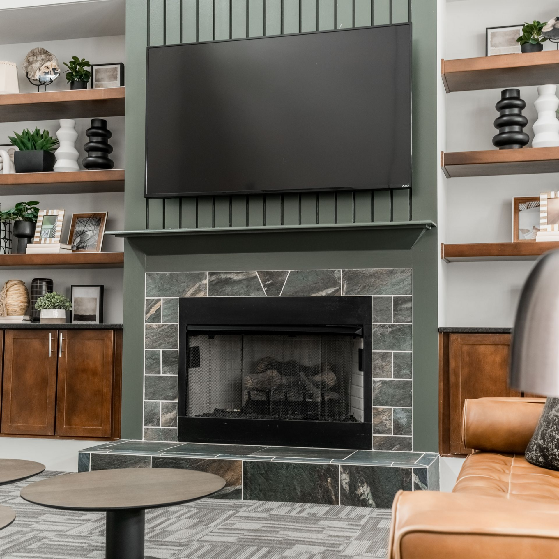 Resident clubhouse with fireplace, TV, built-in shelves, leather couch, and a round coffee table at Willows at Fort Mill, offers 1,2, and 3 bedroom apartments in Fort Mill, SC.