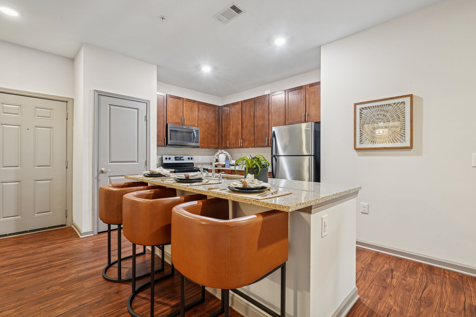 Kitchen with brown cabinets, stainless steel appliances, and a breakfast bar with brown leather stools at Willows at Fort Mill, offers apartments in Fort Mill, SC.