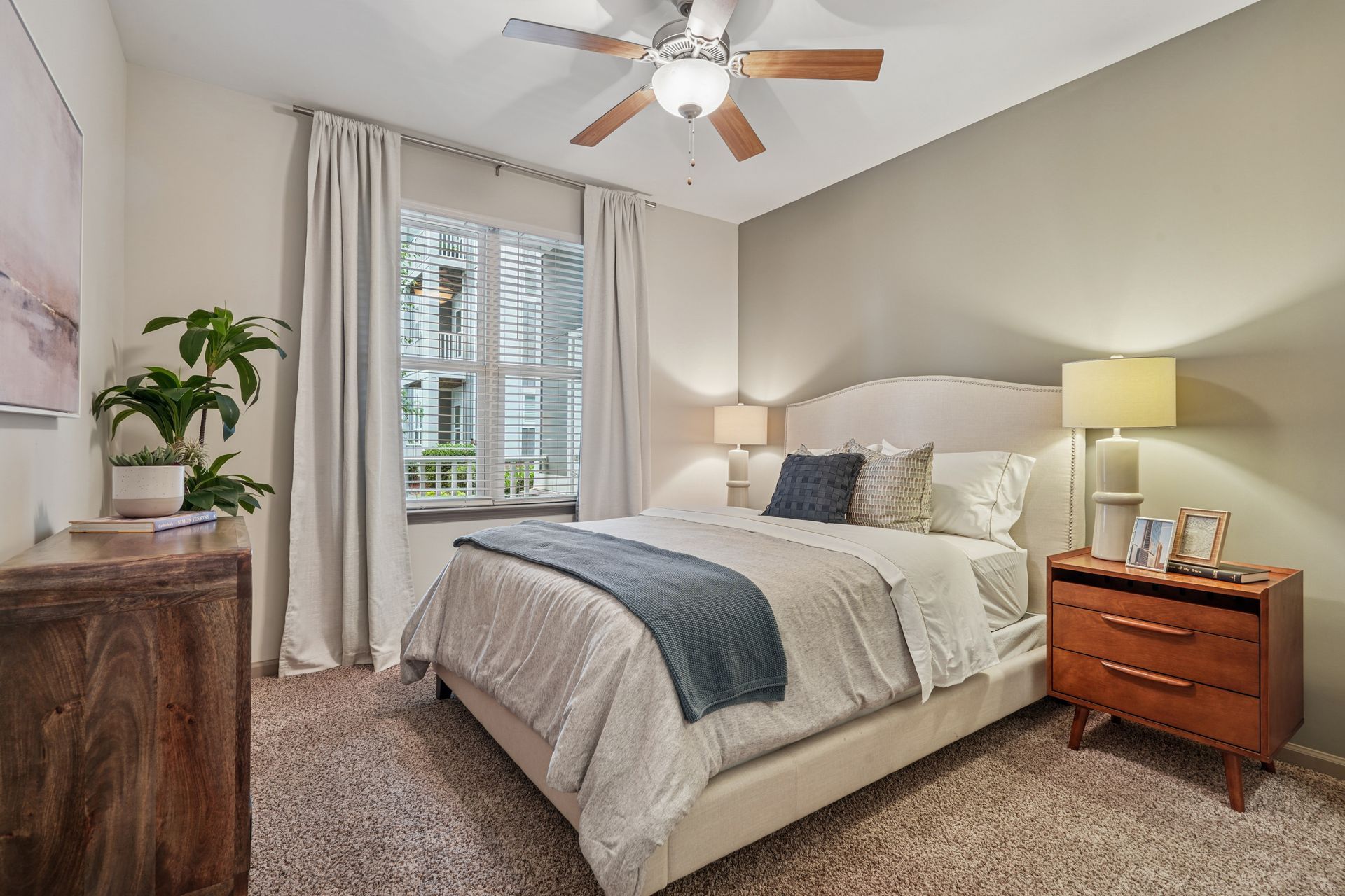 Bedroom with bed, nightstand, window, dresser, and green plant at Willows at Fort Mill, offers Fort Mill apartments for rent in SC.