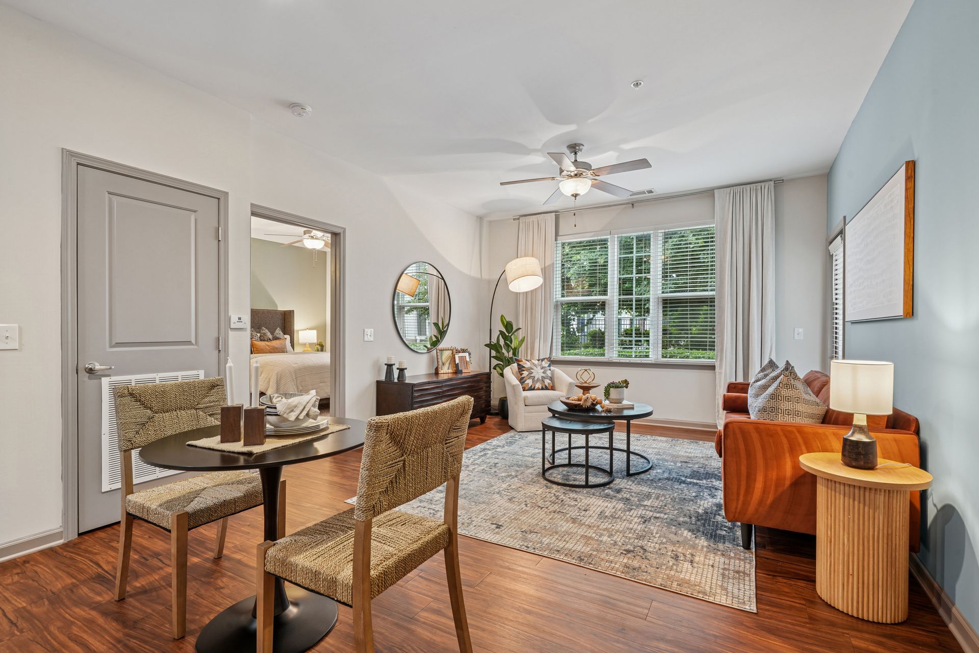 Living room with dining table, orange sofa, and neutral decor at Willows at Fort Mill, offers Fort Mill apartments near Downtown.
