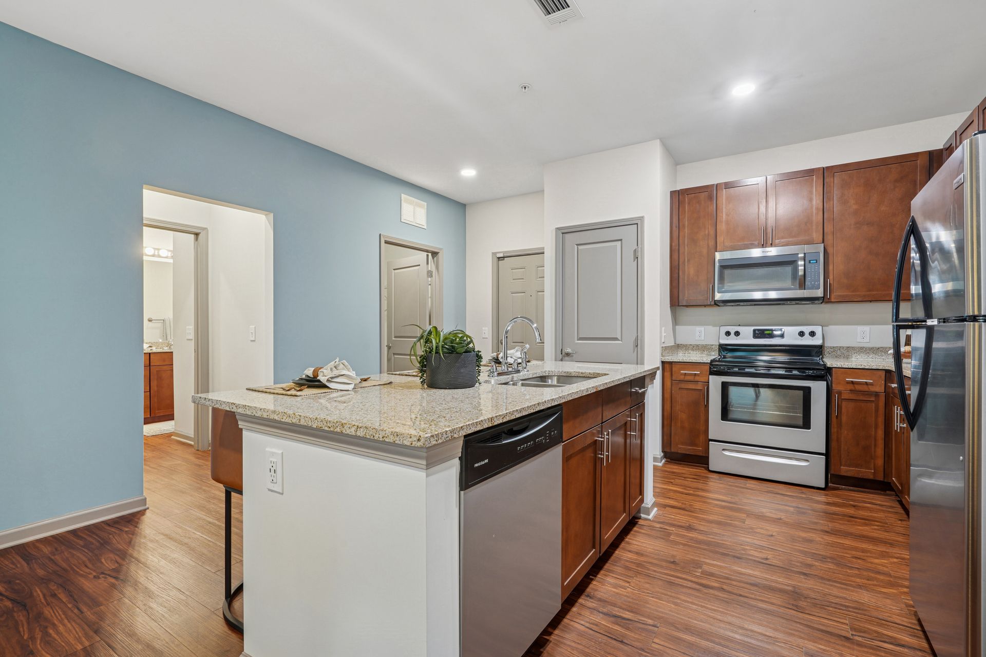 Kitchen with island, stainless steel appliances, wood cabinets, and blue wall at Willows at Fort Mill, offers apartments for rent in Fort Mill, SC.