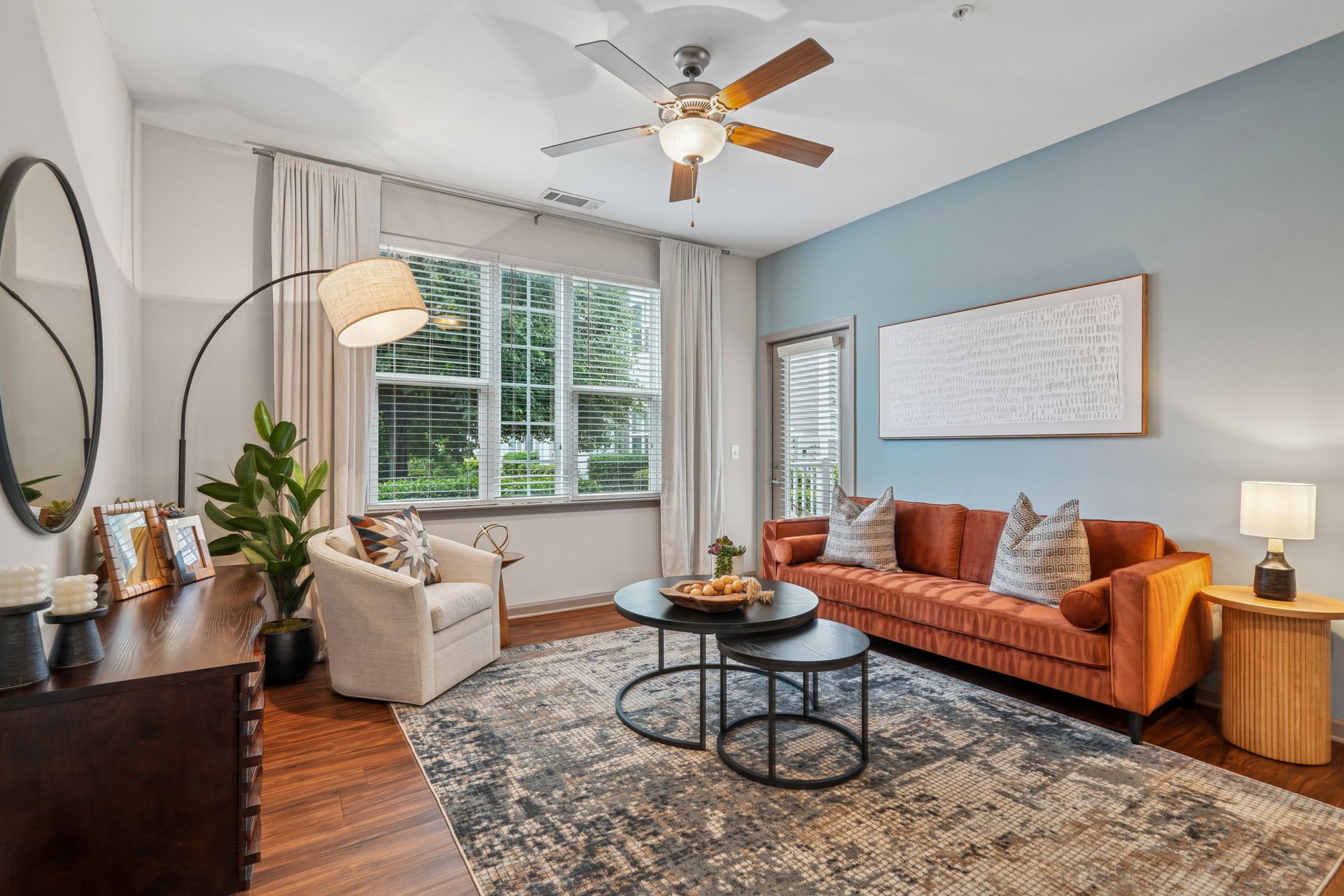 Living room with orange couch, blue wall, large window, and rug at Willows at Fort Mill, offers Fort Mill apartments near Downtown.