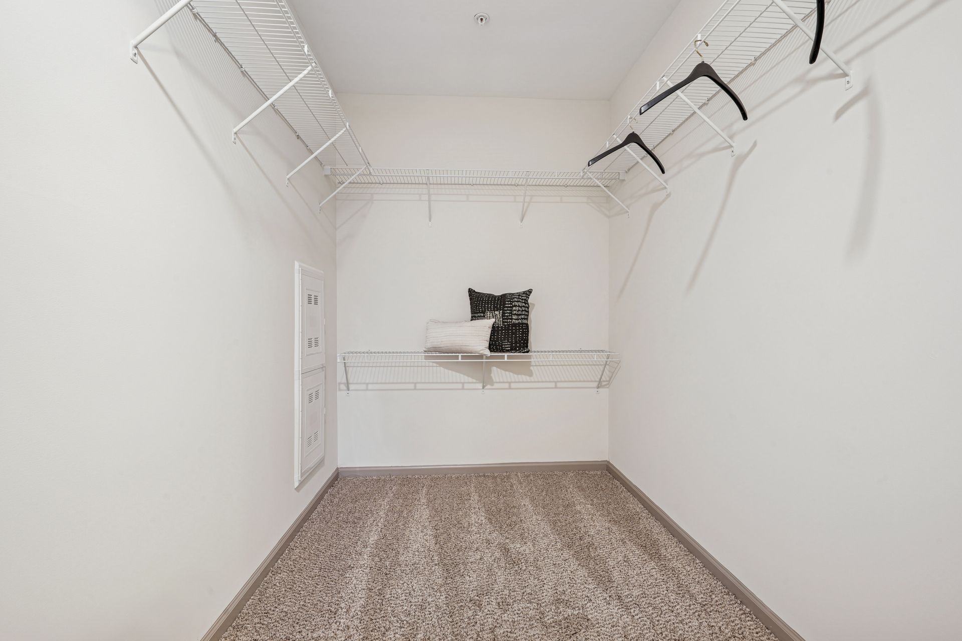 Empty walk-in closet with wire shelving, carpet, and some hangers at Willows at Fort Mill, offers Fort Mill apartments for rent.