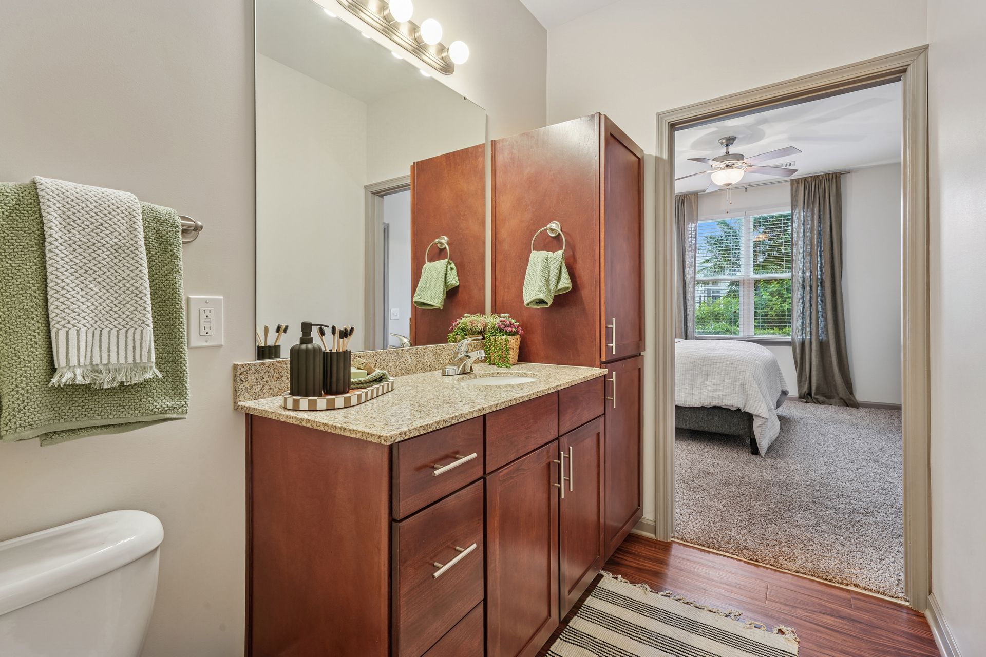 Bathroom with a vanity, mirror, and open doorway to a bedroom with a bed at Willows at Fort Mill, offers Fort Mill apartments for rent in SC.