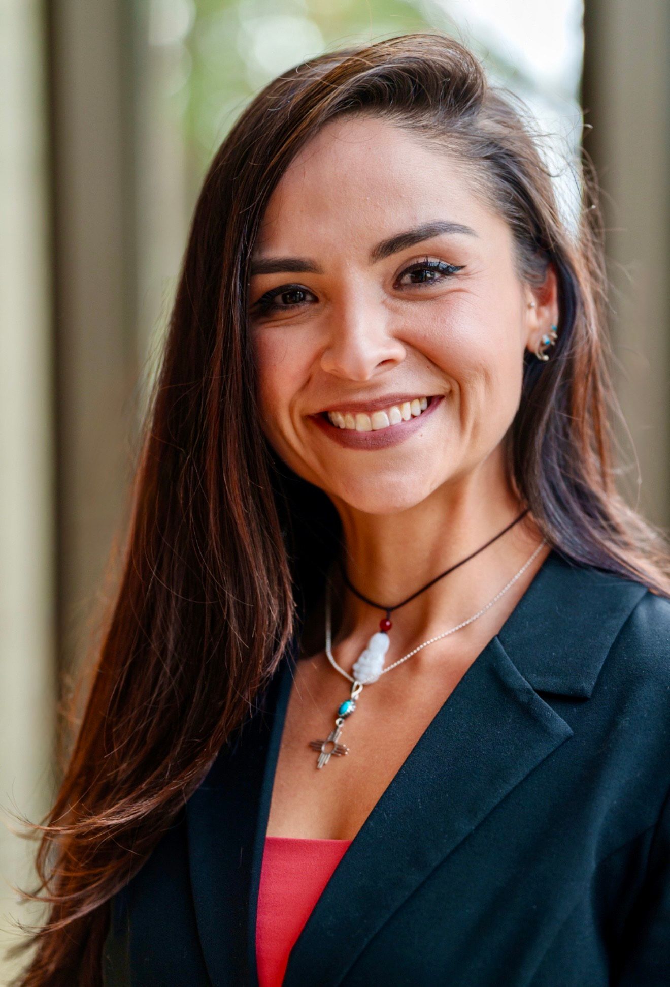 A woman wearing a brown hat with feathers on it is smiling.