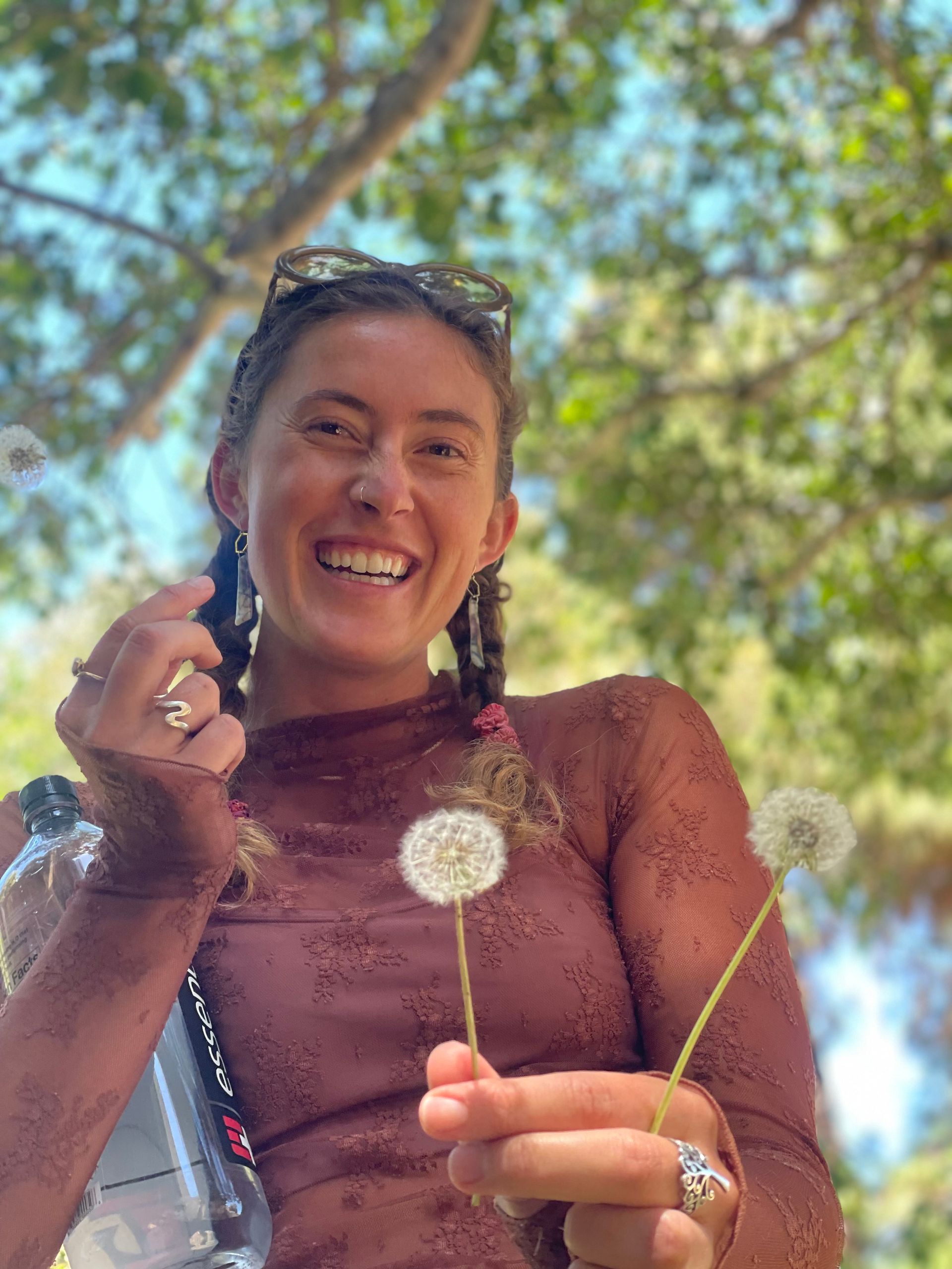 A woman wearing a brown hat with feathers on it is smiling.
