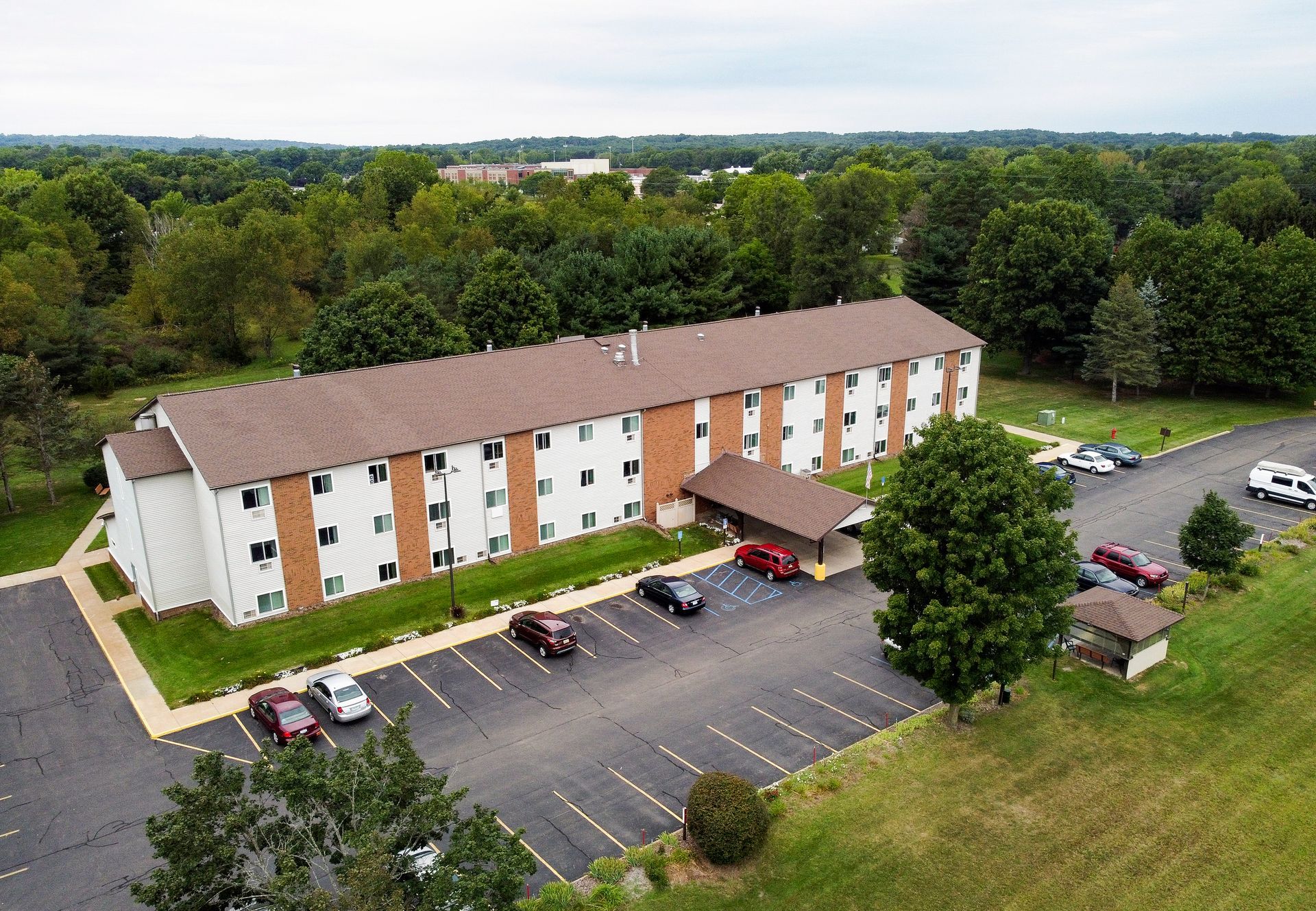 An aerial view of a large apartment building with cars parked in front of it.