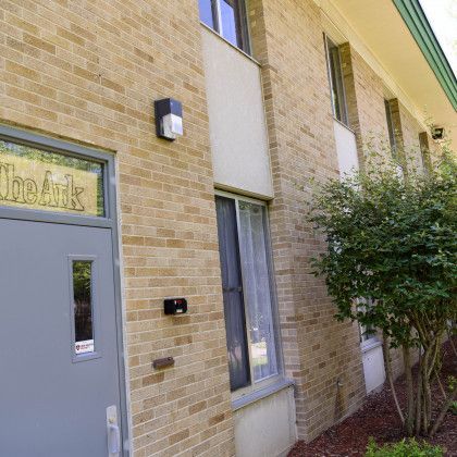 A brick building with a gray door and a tree in front of it