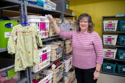 A woman is standing in a room holding a basket of clothes.