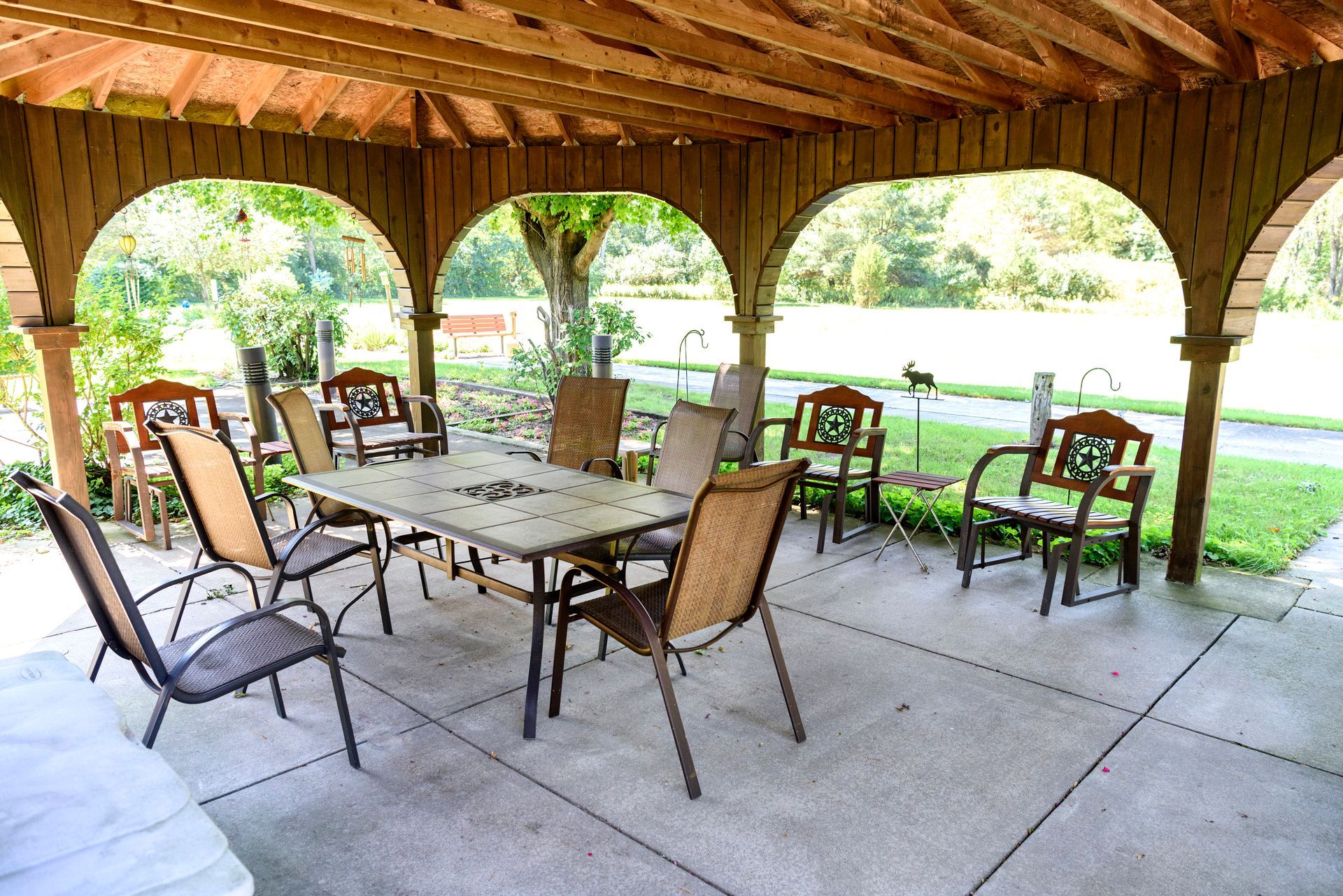 A patio with a table and chairs under a wooden structure.