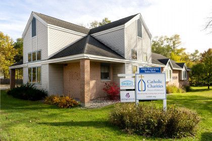 A white house with a sign in front of it that says catholic churches.