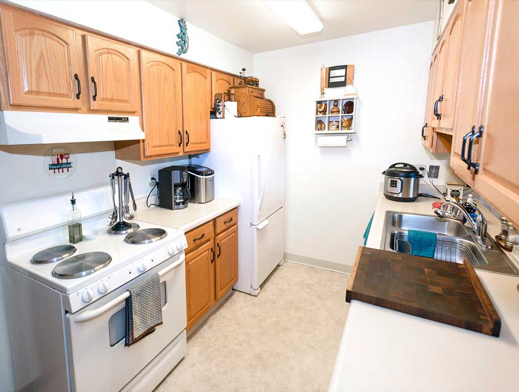 A kitchen with a stove , refrigerator , sink and wooden cabinets