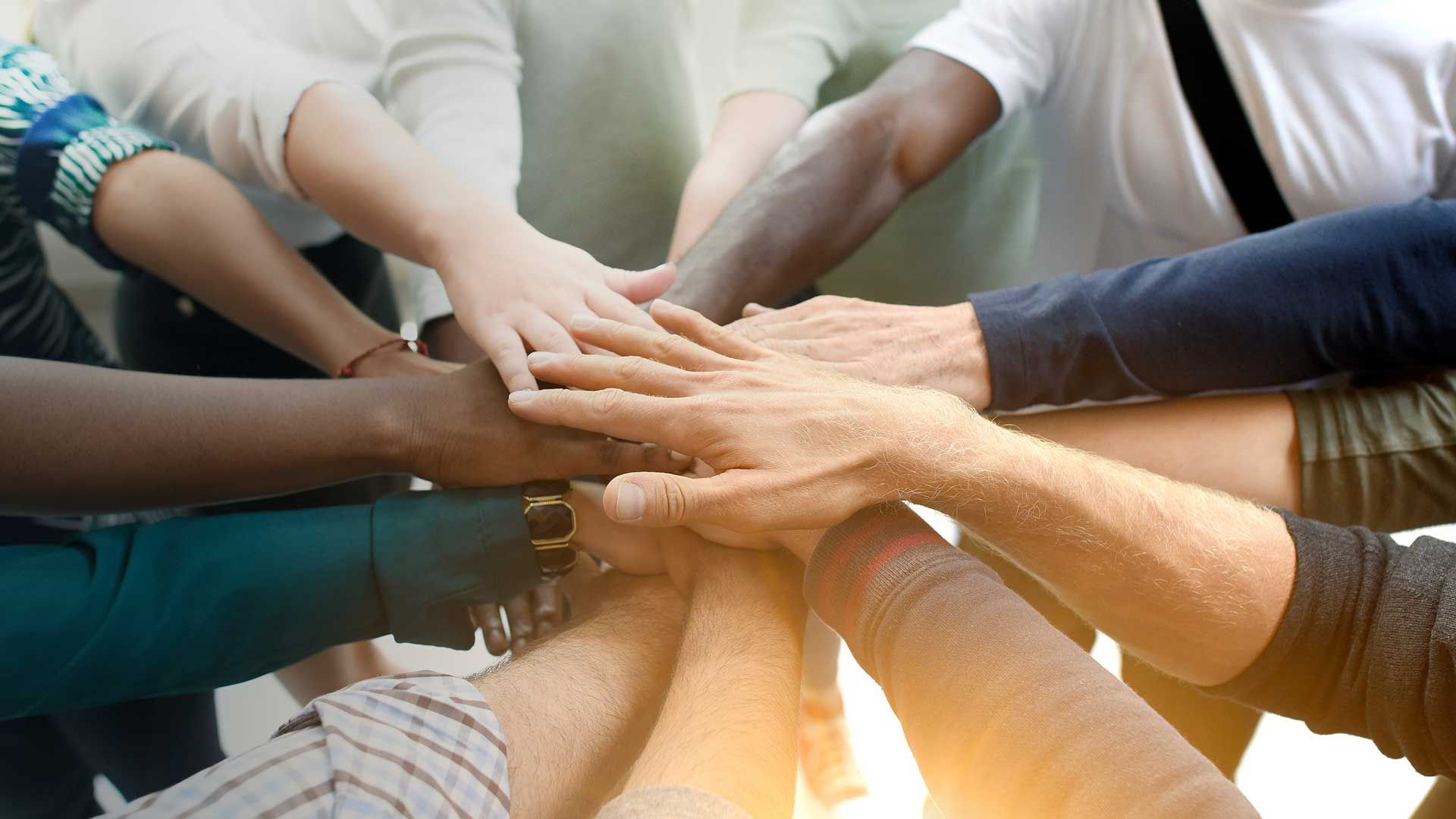 A group of people are putting their hands together in a circle.
