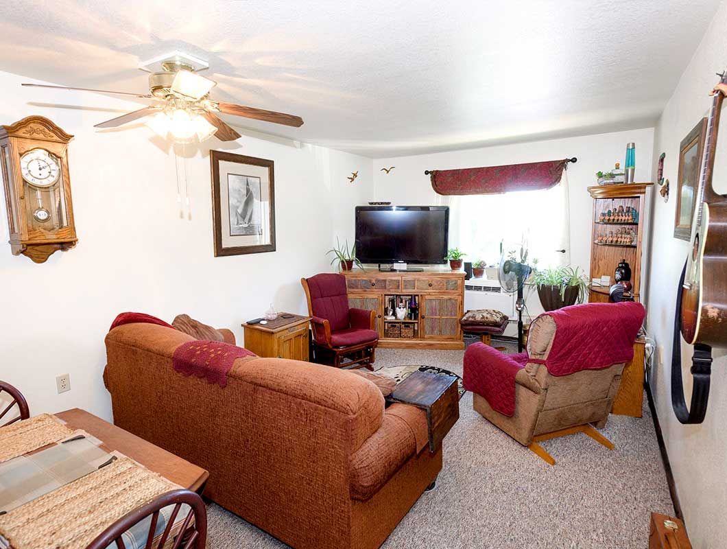 A living room with a couch , chair , table and television.