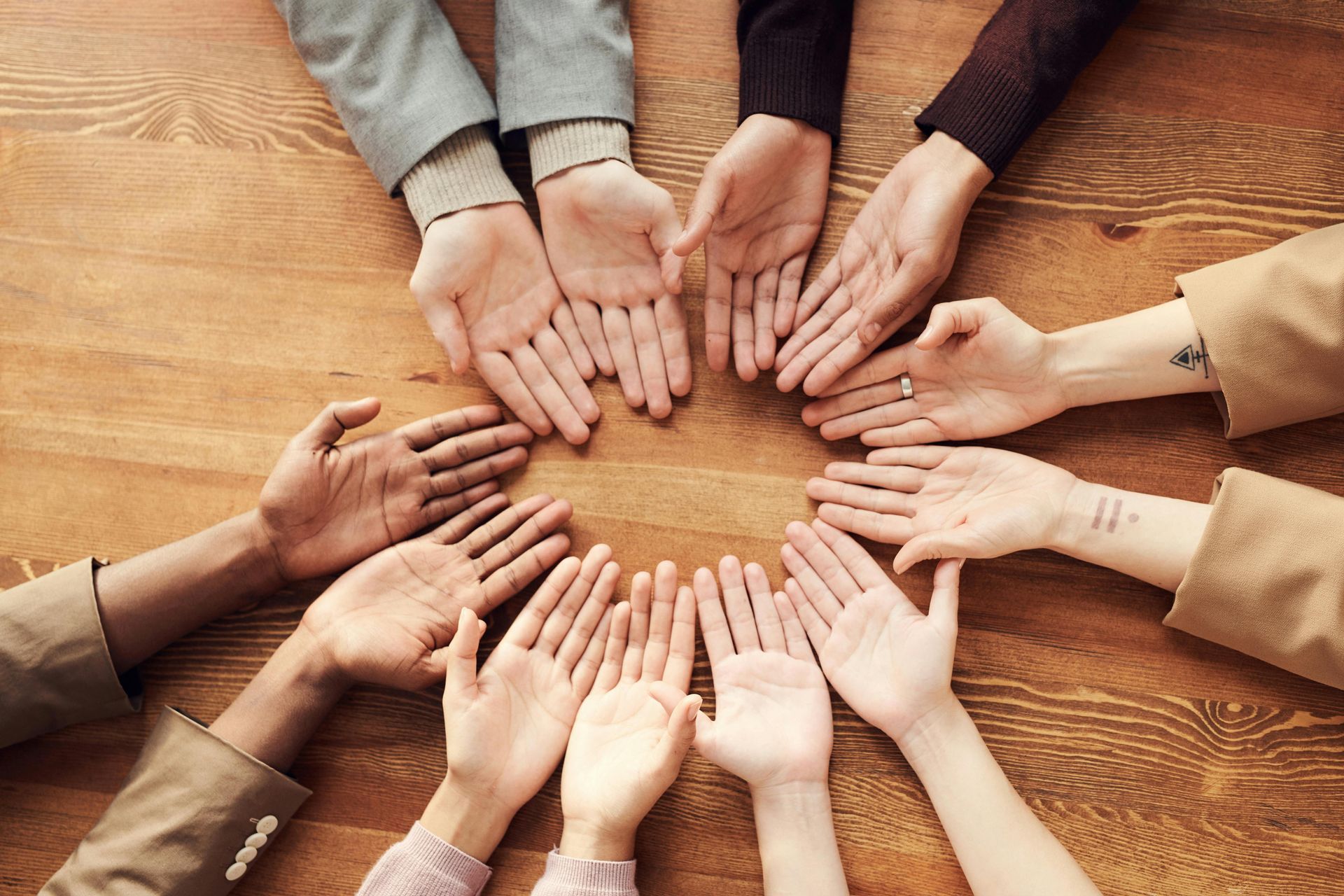 A group of people are putting their hands together in a circle.