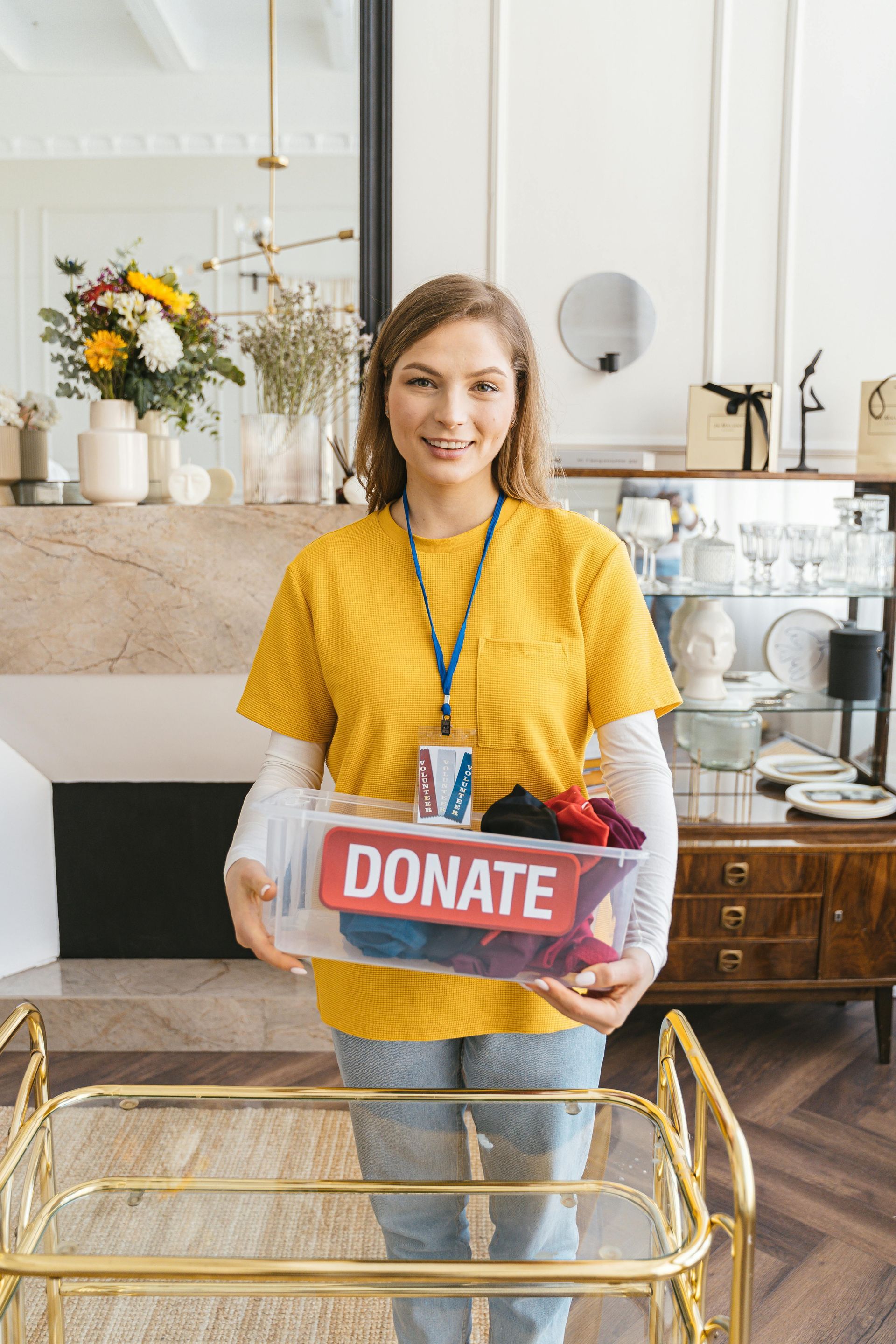 A woman in a yellow shirt is holding a donate box.